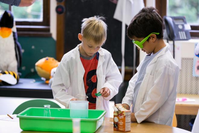 Two students wearing lab coats in science class