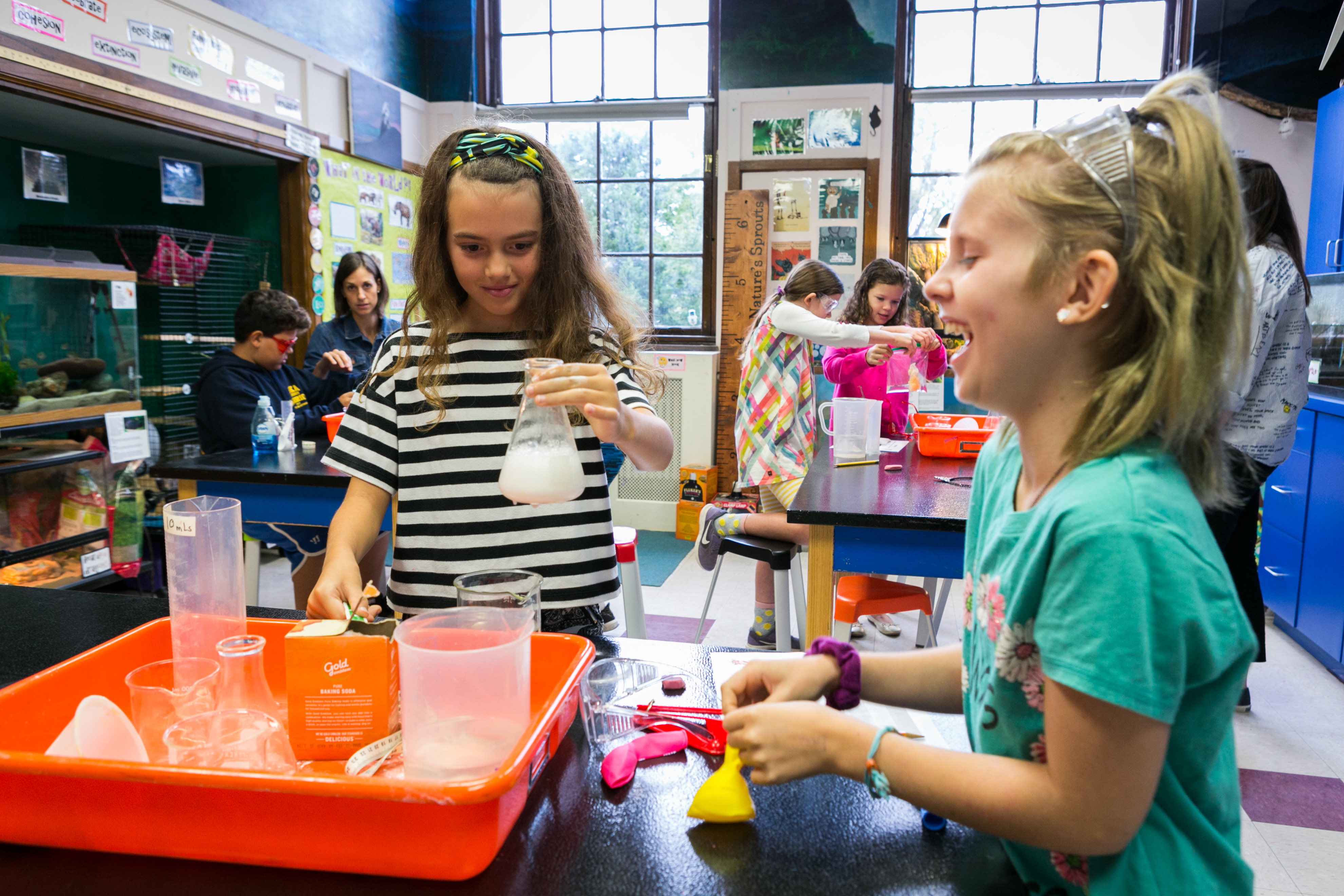 Two girls work on science experiment using beakers