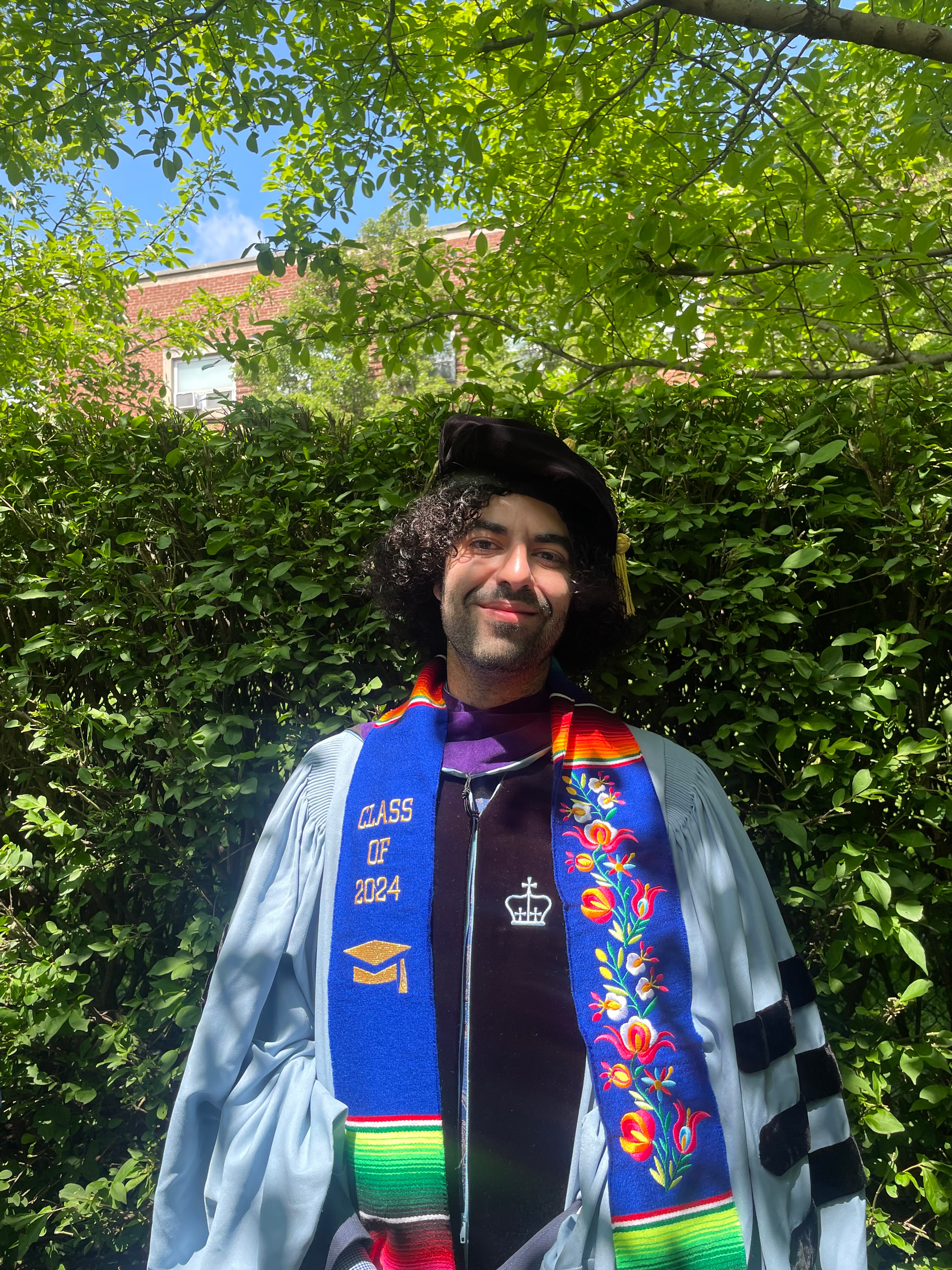 Camilo Rivera standing outside in graduation attire