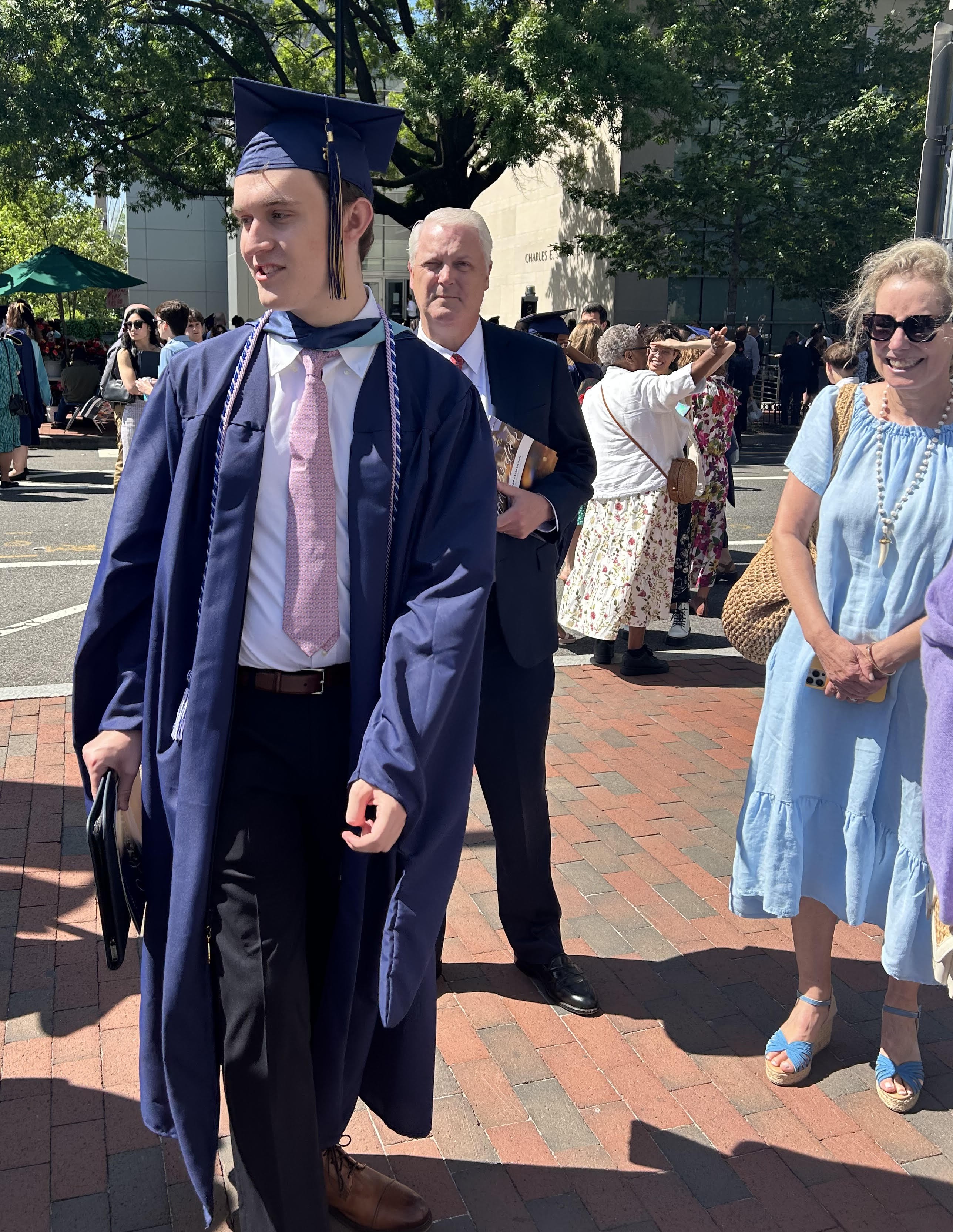 Davis in graduation gown and cap standing outside with family
