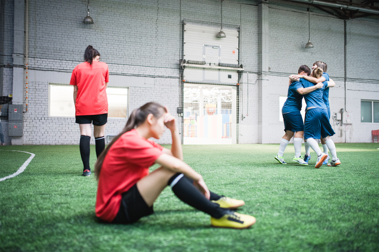 girl sitting on ground upset after soccer match