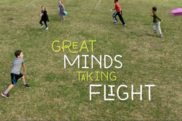 Kids running in field with paper airplane