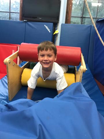 A student smiling while using occupational therapy equipment