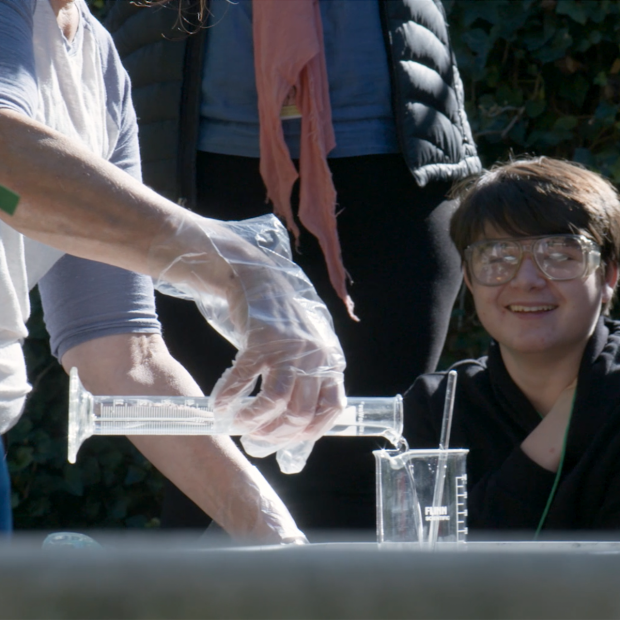 Teacher pours unknown liquid from chemistry beaker