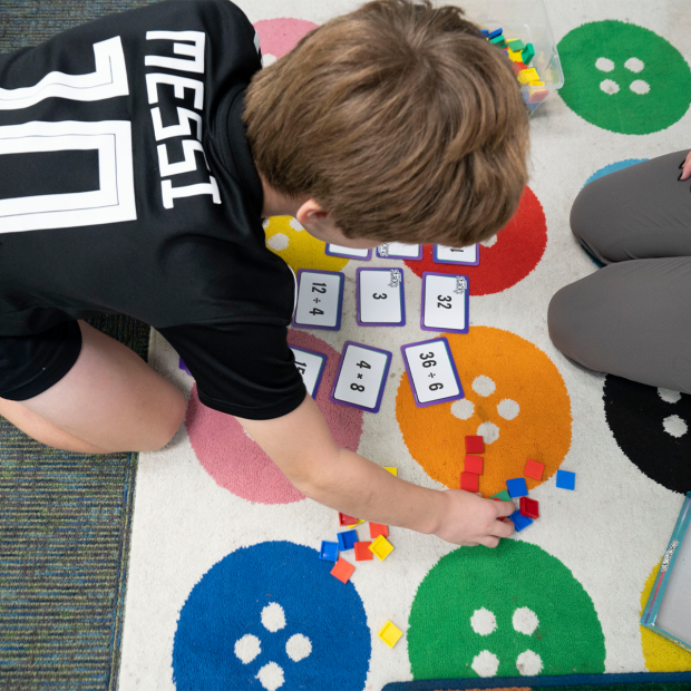 A student on the floor using math flashcards