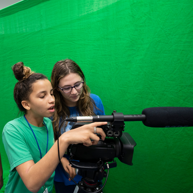 Two students using camera in front of a green screen