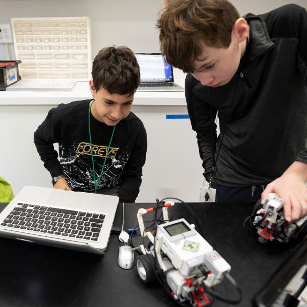 Two students standing over car robot they built