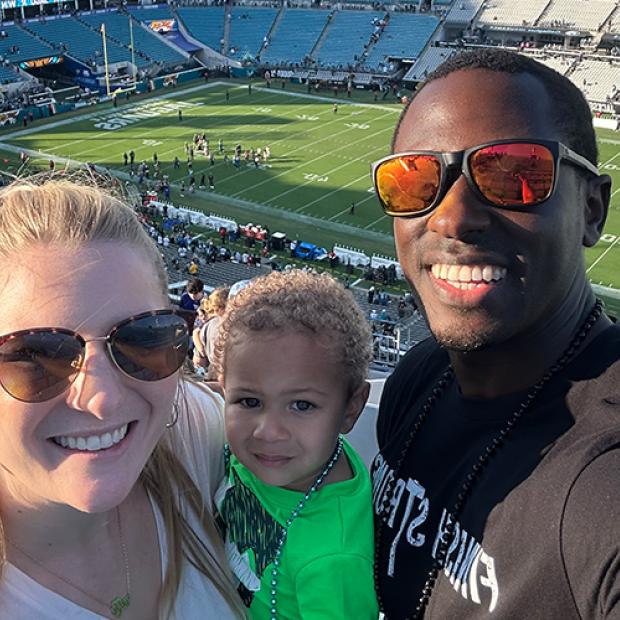 Demetri with wife and child at football stadium