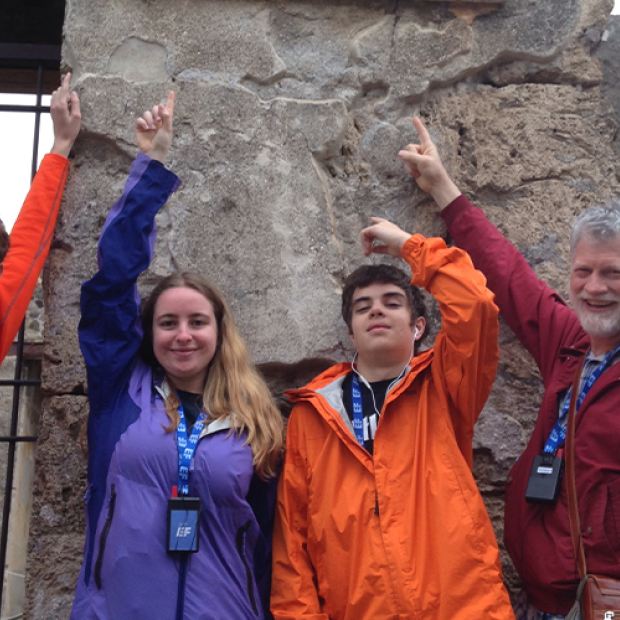 Davis with three people standing in front of a natural rock wall. 