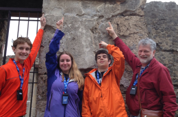 Davis with three people standing in front of a natural rock wall. 