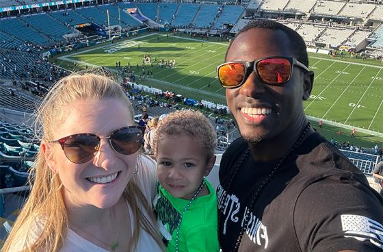 Demetri with wife and child at football stadium