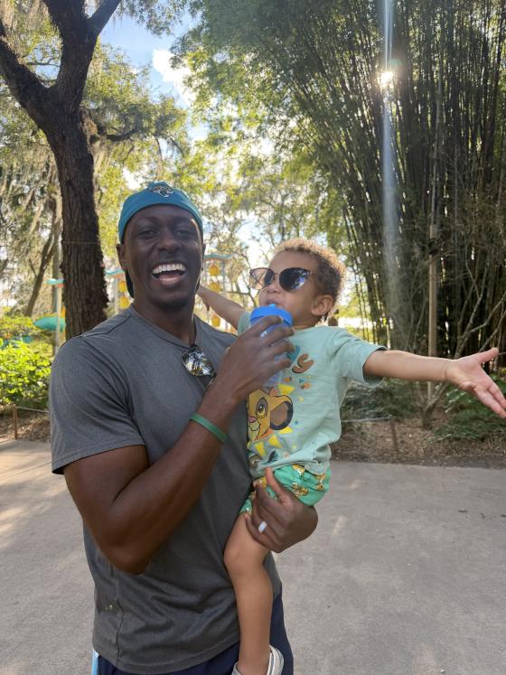 Demetri smiling while holding baby