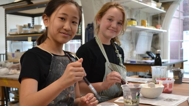 Two students smiling at camera in Intermediate art class
