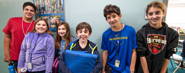 Group of junior high students standing in classroom smiling