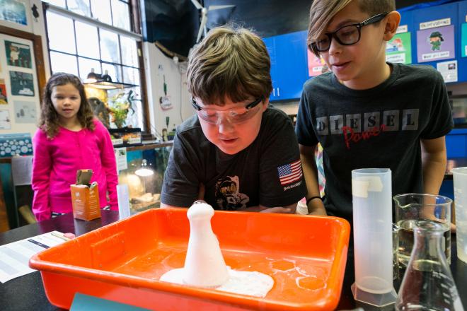 Two students looking at foaming thing in science class