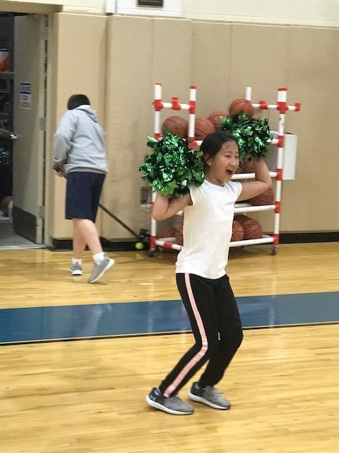 girl in gymnasium with pom-poms