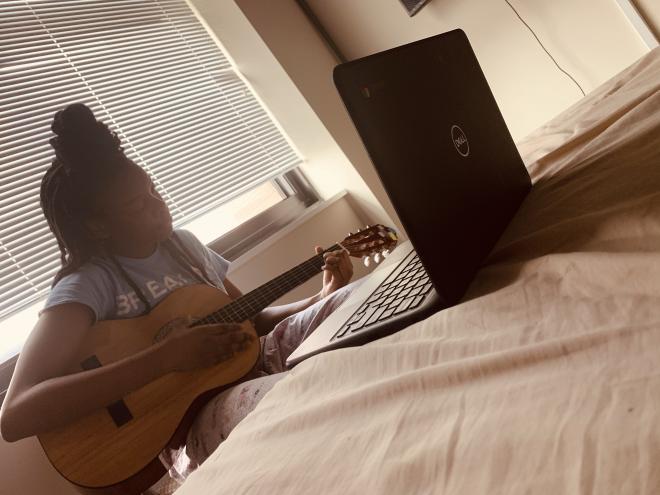 girl plays guitar on bed