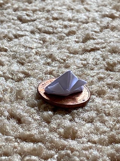 tiny origami boat on top of a penny