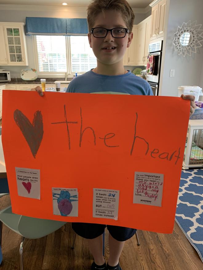 student stands in kitchen holding poster