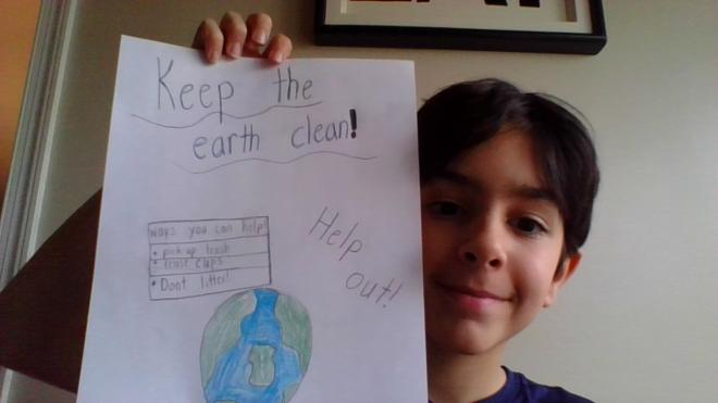 Student holds up drawing of the earth