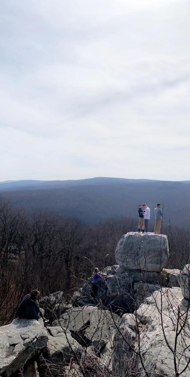 students standing on rock with mountains in background