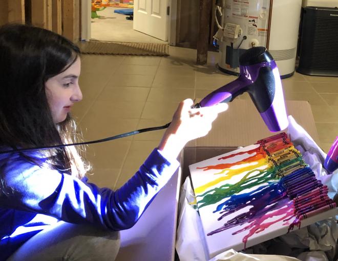 student using blowdryer to melt crayon art