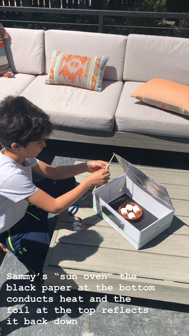 student sits on porch opening box