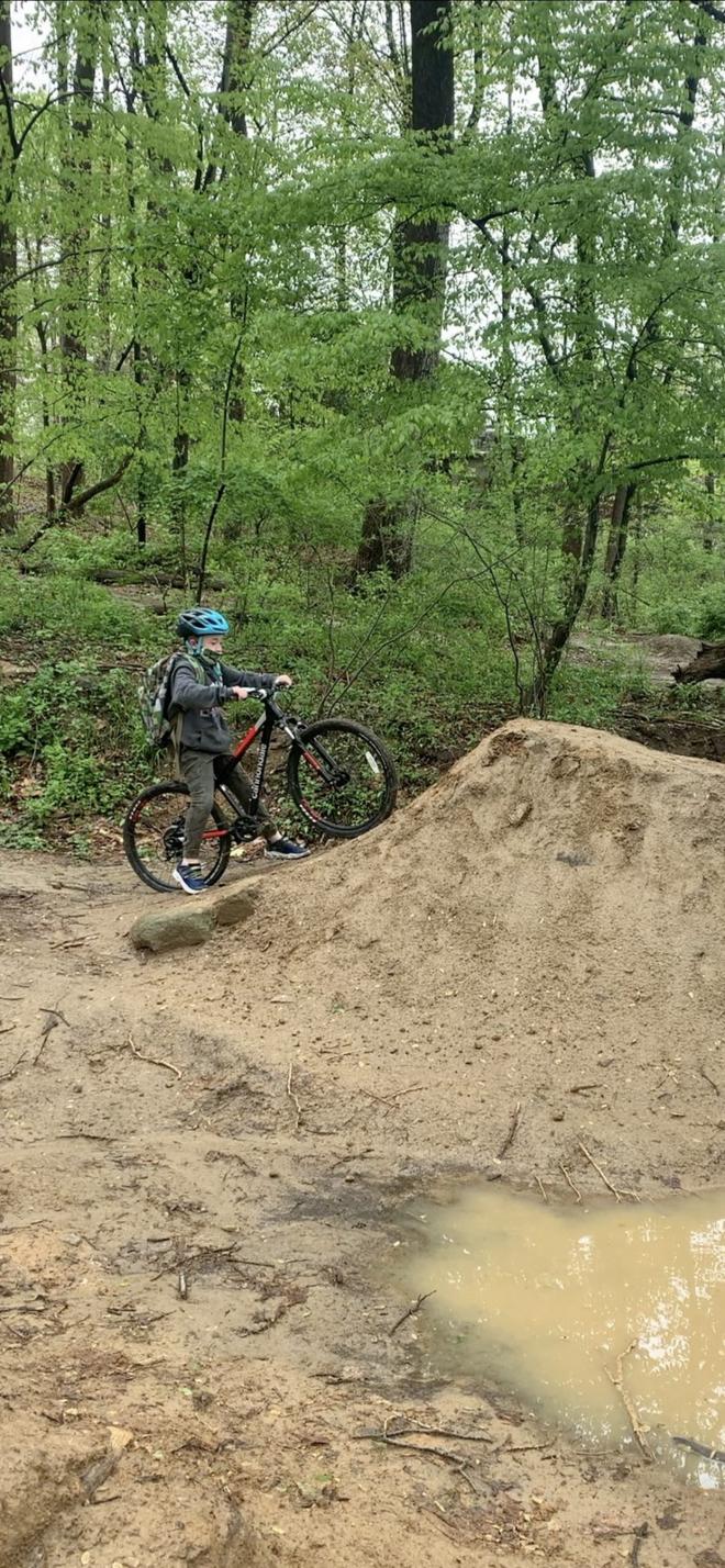 student rides bike up a dirt hill