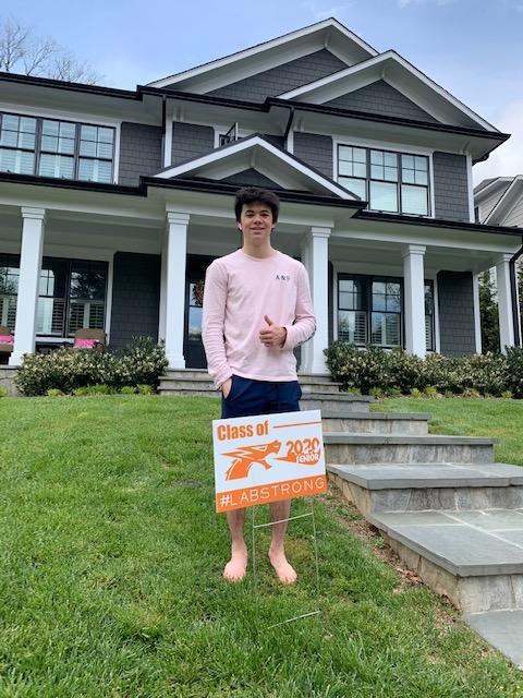 Senior student stands in yard with sign